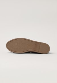 Suola di scarpa in gomma marrone con superficie testurizzata, forma curva e motivo in rilievo lungo i bordi per presa e durata.