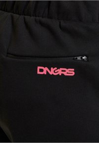 Crne trenirke od teksturiranog materijala, s ružičastim logotipom "DNGRS" i malim crnim džepom sa zatvaračem sa strane.