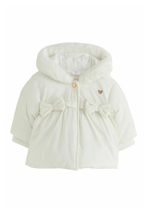 Manteau bébé blanc avec une capuche duveteuse, deux nœuds en tissu à l'avant, un petit détail en forme de cœur et une fermeture à boutons à l'avant.