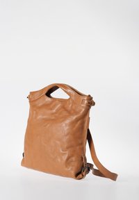 Tasche aus tanfarbenem Leder mit weicher Textur, minimalistisches Design, Obergriff, verstellbarer Schulterriemen und seitlichen Schnallen zur Schlie?ung.