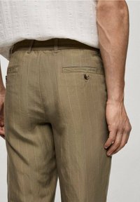 Kašmírové proužkované kalhoty s elastickým pasem, dvěma zadními kapsami a světlými švy jako dekorativními prvky. Tkanina vypadá hladká a lehká.