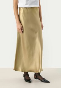 Gonna maxi in raso dorato con una superficie liscia, caratterizzata da una silhouette dritta e una lucentezza sottile, abbinata a scarpe nere con punta appuntita.