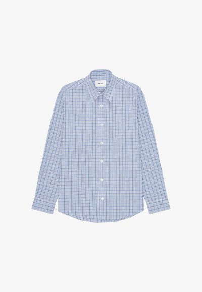 Chemise à manches longues boutonnée avec motif à carreaux bleu et blanc, col pointu et ourlet arrondi, posée à plat sur fond blanc.