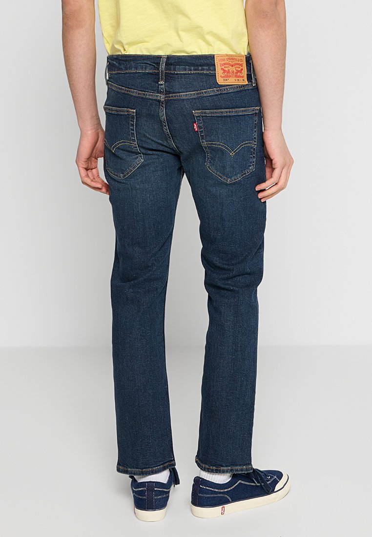 Dunkelblaue Denim-Jeans mit geradem Bein, ausgestattet mit einem markierten Lederpatch am hinteren Bund und Taschen mit einem auffälligen Nähmuster.