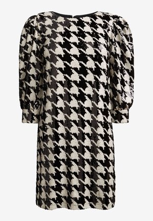 Vestido de lentejuelas en pata de gallo blanco y negro, con mangas largas abullonadas y cuello redondo.