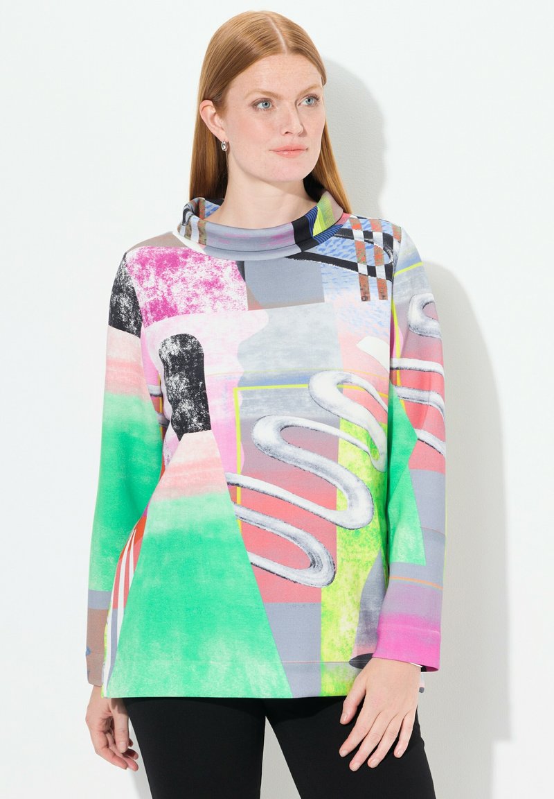 Top de manga larga con cuello de cowl que presenta un patrón abstracto multicolor con elementos en verde, rosa, gris y negro. Textura de tela suave.