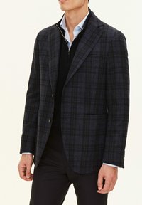 Mörkblårutig kavaj med en strukturerad design, tillverkad av ulltyg. Har slagkragar, två framfickor och en enkel knappstängning.