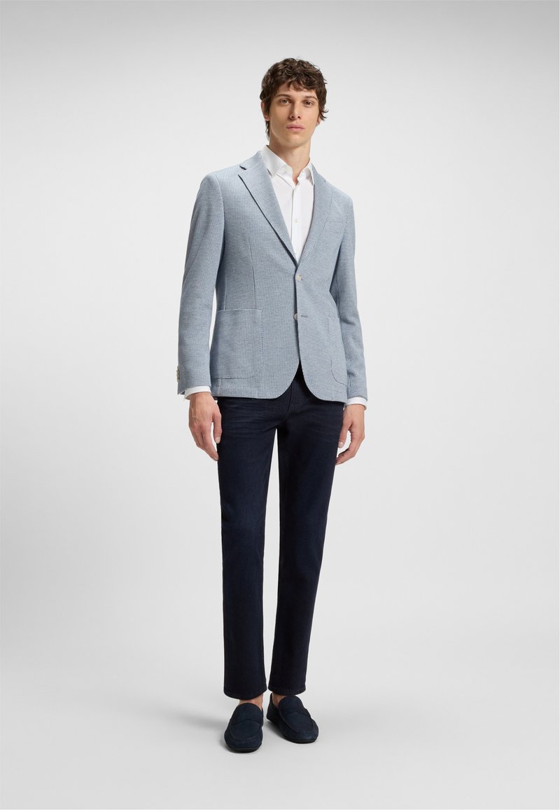 Blazer a cuadros azul claro, camisa blanca, pantalones oscuros de marina y zapatos de slip-on navy. El blazer cuenta con dos bolsillos frontales y un cierre de un solo botón.