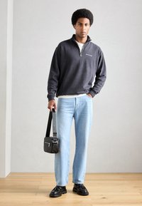 Mørkegrå zip-up sweatshirt, lyseblå lige bukser, sorte lædersko og en lille tekstureret sort crossover taske.