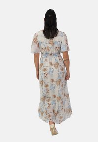 Robe maxi fleurie avec des manches courtes, taille élastique, tissu principalement blanc avec des motifs de fleurs beiges et bleus, et une silhouette fluide.