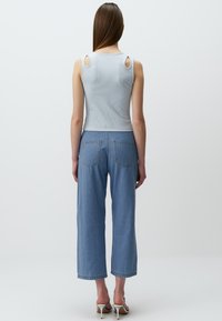 Top in raso celeste a coste con dettagli sulle spalle a taglio, abbinato a jeans larghi celesti, con tasche posteriori e orlo sfilacciato.
