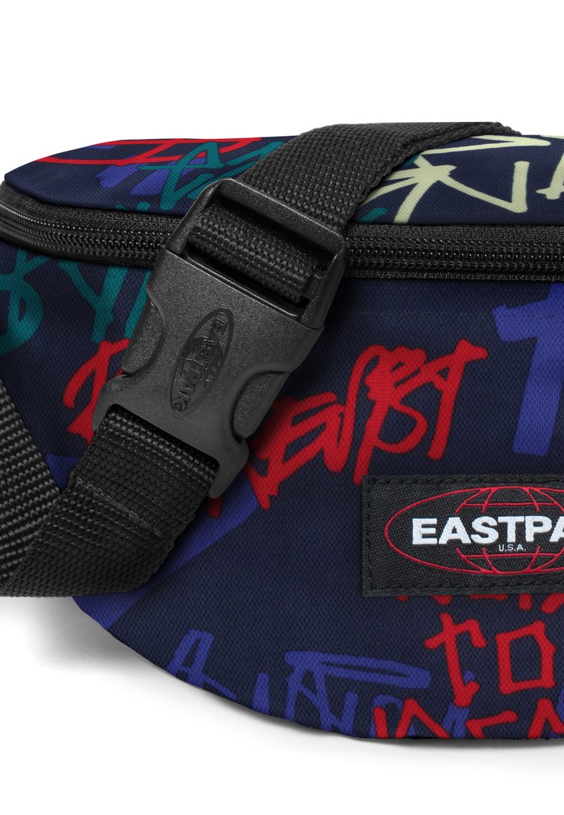 Fanny pack rond en tissu bleu marine avec des motifs multicolores de style graffiti, fermetures éclair durables et une sangle à boucle noire. Logo Eastpak présent.