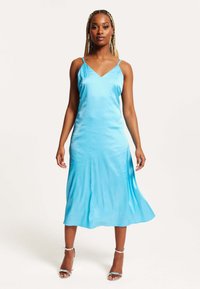 Satin slip dress in bright blue with a v-neck and thin straps, featuring a flowing hemline that falls below the knee.