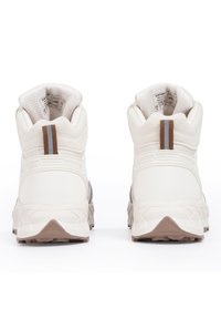 Bílé vysoké tenisky s texturovaným povrchem, hnědým akcentem na patě a vícebarevnou gumovou podrážkou.