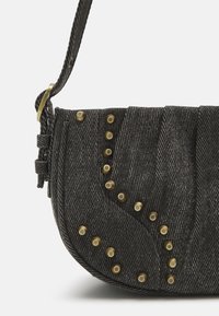 Zwarte denim handtas met een gebogen vorm, textuurpatroon en messing studs. Inclusief een gevlochten schouderband met verstelbare hardware.