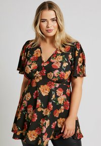 Svart blommig tunika med korta ärmar, prydd med stora orangea, rosa och gröna blommor. V-ringad design med utsvängd fåll.