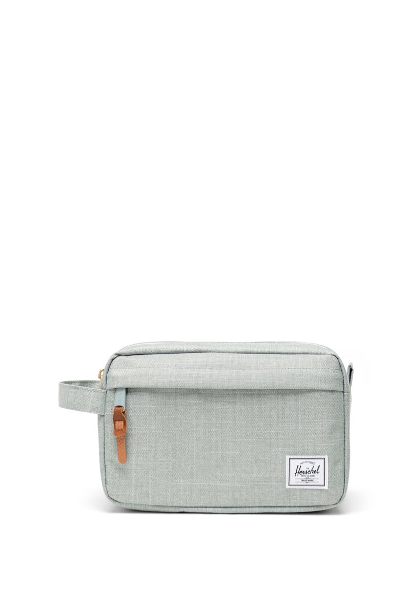 Grå stofpung med en glat tekstur, der har en frontlomme med lynlås og et læderdetaljehåndtag. Logoetiket på forsiden.