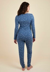 Set de pijamale cu un model albastru, prezentând un design cu stele, mâneci lungi și picioare ajustate, realizat dintr-un material moale. Decolteu și manșete neajustabile.