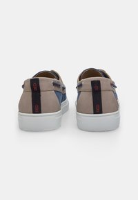 Sneaker in suede e denim con blocchi di colore grigio e blu, suola in gomma bianca e dettaglio rosso del logo sul retro. Design a profilo basso.