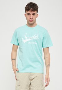 T-shirt in cotone verde menta con logo grafico bianco "Sundek CALIFORNIA". Le maniche corte e il collo a giro completano il design.