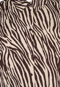 Kraevi särgil on beež ja pruun zebra triibuline muster, peene tekstuuriga ning ees viie musta nööbiga.