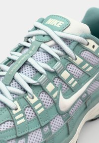 Nike tenisice s mrežastim gornjim dijelom u mint zelenoj boji s bijelim naglascima, teksturiranim preklopima i istaknutim bijelim Swoosh logom.