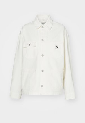 Veste en coton blanc avec un devant à boutons, deux poches sur la poitrine et un patch logo carré. Coupe décontractée avec des manches longues et des coutures visibles.