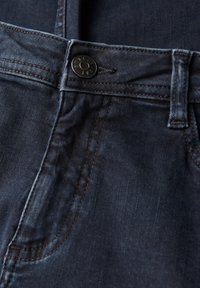 Tmavě modré džínové kalhoty s knoflíkovým zapínáním, viditelným prošíváním a zakřivenou kapsou. Materiál má hladkou strukturu a minimální blednutí.