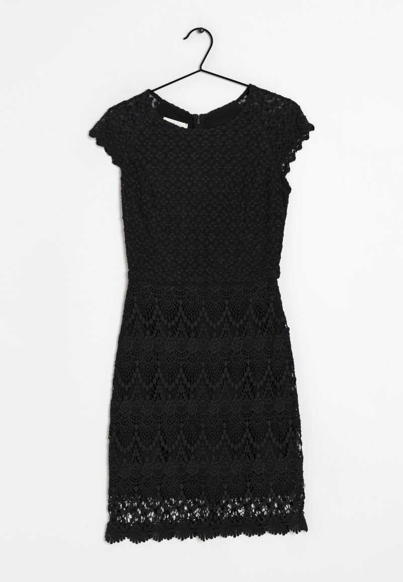 Robe courte en dentelle noire à manches courtes avec motifs floraux, taille ajustée et ourlet festonné, accrochée à un cintre noir sur un fond blanc.