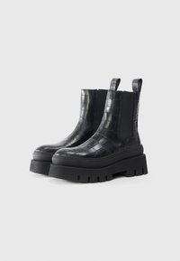 Black leather ankle boots with crocodile texture, elastic side panels, and thick black lug sole for grip and durability.