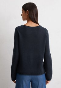Dunkelblauer Strickpullover mit langen Ärmeln und rundem Ausschnitt, der eine strukturierte Oberfläche und eine lockere Passform hat.