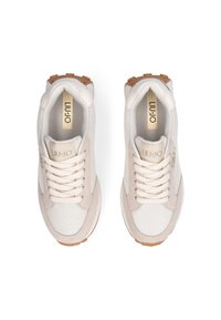 Hvide og beige sneakers med mesh- og ruskindsmaterialer, rund tåform, snørebånd, tekstureret sål og guld logo accenter på tungen og siden.