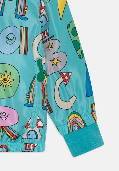 Colorful children's jacket in lightweight material, featuring a turquoise base with playful patterns including smiley faces and shapes. Zippered pocket.