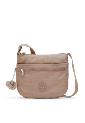 Beige Umhängetasche mit vorderer Reißverschlusstasche, verstellbarem Schulterriemen, rundem Logopatch und angebrachtem Plüsch-Affen-Schlüsselanhänger.