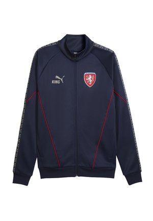Marineblauw sportjack met ritssluiting, rode biezen, Puma-logo, "KING" tekst en een rood schildembleem met twee leeuwen op de borst.