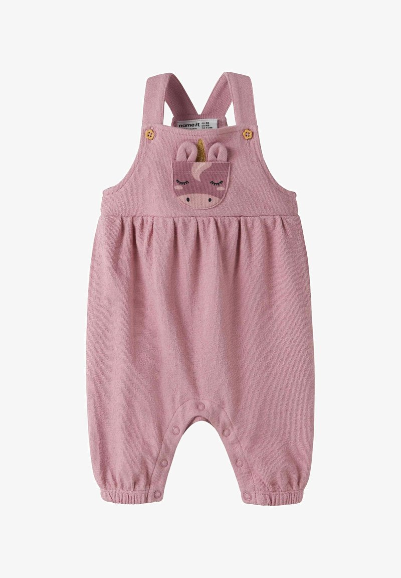 Barboteuse tricotée rose pour bébé avec bretelles, boutons-pression aux jambes et un patch visage de licorne sur la poche poitrine.