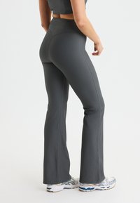 Grijze geribbelde flared leggings met een hoge tailleband, die een textuur afwerking en een nauwsluitende silhouet bieden, gecombineerd met witte sportschoenen.