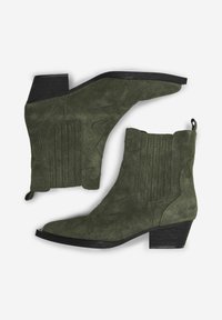Botine verzi din suede, până la gleznă, cu toc pătrat, care au cusături decorative și un tab de prindere. Designul include crestături pe panourile laterale și vârf ascuțit.