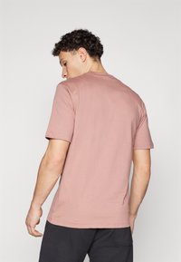 Korte mouwen, ronde hals t-shirt in stoffige rozenkleur van katoen. Kenmerkt zich door een eenvoudige uitstraling zonder patronen, een zachte textuur en een standaard pasvorm.