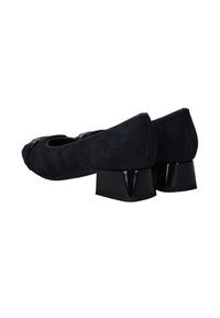 Chaussures à talon carré en daim noir avec un bout rond, présentant un accent noir brillant sur le talon et une texture lisse.