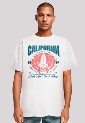 White cotton t-shirt with a round neckline featuring a graphic print of palm trees, a surfboard, and a skull in teal and red colors.