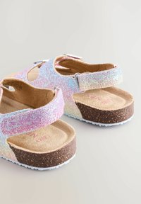 Glitzernde rosa und schillernde Sandalen mit verstellbaren Riemen, Korkfußbett und strukturiertem Gummisohle. Offenes Zehendesign mit Ausschnitten.
