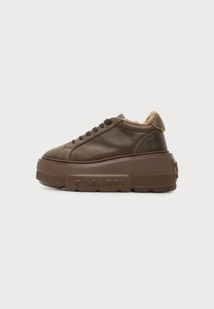 Zapatilla gruesa de cuero marrón con suela gruesa de plataforma y con la marca "Casadei" en el lateral, con forro de piel alrededor del cuello.