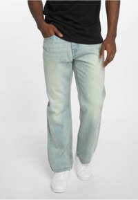 Heledad hall sinine denim-tekstiil, sirge lõikega, pleekinud tekstuuriga, viie taskuga disain ja kerge kulumine ääres. Kanda musta särgi ja valgete tossudega.