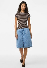 Rudos ir kremiškos spalvos dryžuota prigludusi marškinėlių suknelė derinama su šviesiai mėlynomis džinsinėmis kelnių kelnėmis. Kelnės turi nupjautą apvadą ir laisvą siluetą. Rudi batai užbaigia įvaizdį.