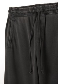 Schwarze Sweatpants aus weichem Stoff mit einem elastischen Bund und Kordelzug, Seitentaschen und einer glatten Textur.