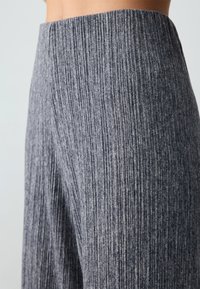 Grijze, ribbelstof broek met verticale textuur, hoge tailleband en een gladde afwerking, die een op maat gemaakte pasvorm en modern design toont.