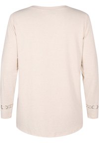 Maglietta beige a maniche lunghe con scollo rotondo, caratterizzata da dettagli in pizzo intricati sulle maniche. Tessuto morbido e leggero con una vestibilità rilassata.
