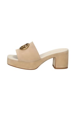 Sandali platform beige con una larga fascetta sulla punta e accessori circolari dorati, dotati di un tacco a blocco e una texture in pelle liscia.