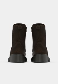 Tumši brūni zamša potīšu zābaki ar gludu apdari, sānos rāvējslēdzēji, pastiprināts papēdis un izturīga melna gumijas zole.